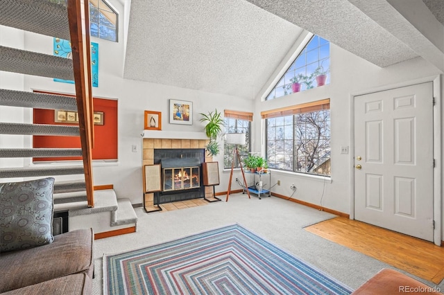 living room with high vaulted ceiling, carpet floors, a tile fireplace, and a textured ceiling