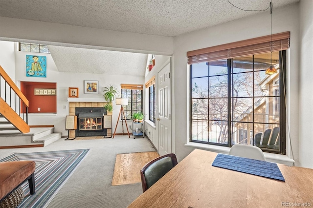 interior space with a textured ceiling, a tile fireplace, and a healthy amount of sunlight