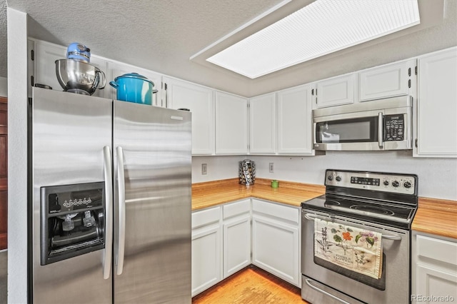 kitchen featuring white cabinetry, stainless steel appliances, and a textured ceiling