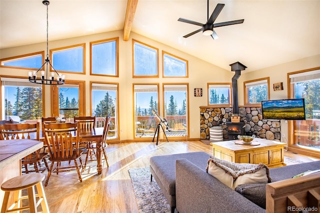 living area featuring plenty of natural light, beamed ceiling, light wood-type flooring, and a wood stove