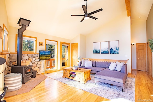 living room with a ceiling fan, a wood stove, high vaulted ceiling, and wood finished floors