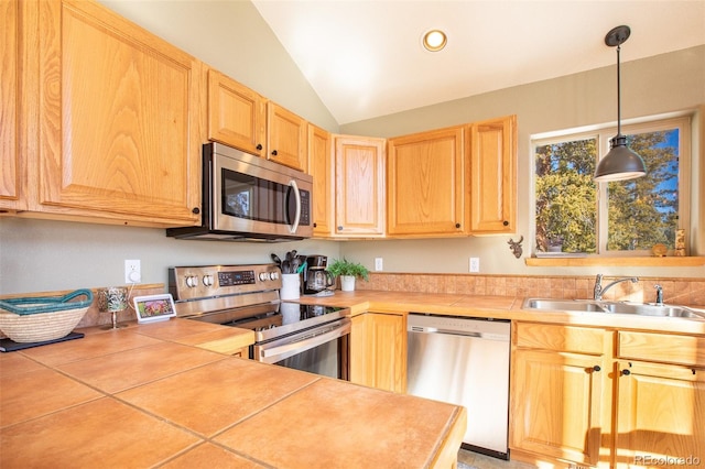 kitchen featuring stainless steel appliances, a sink, vaulted ceiling, light countertops, and light brown cabinetry