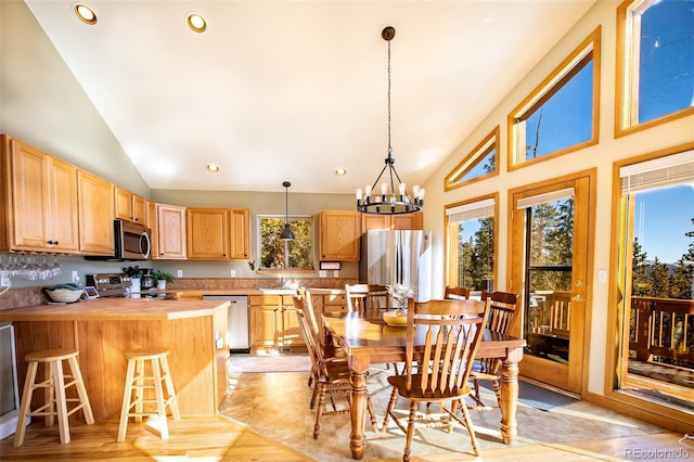 dining space with light wood-type flooring, high vaulted ceiling, a notable chandelier, and recessed lighting