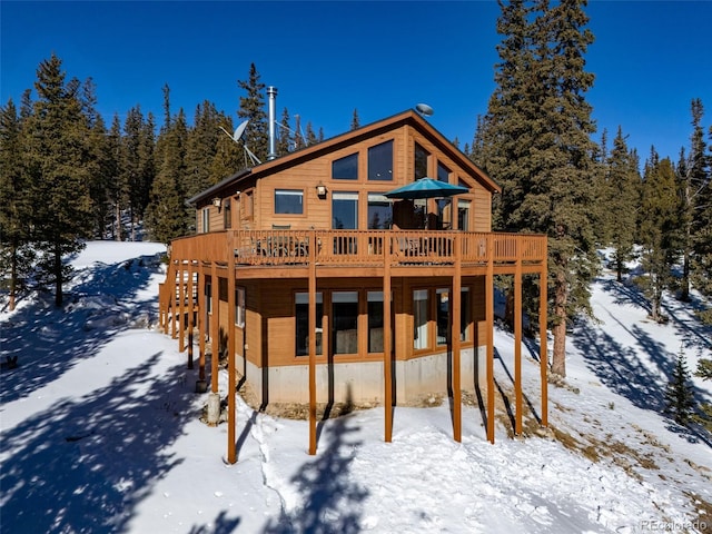 snow covered house with a wooden deck