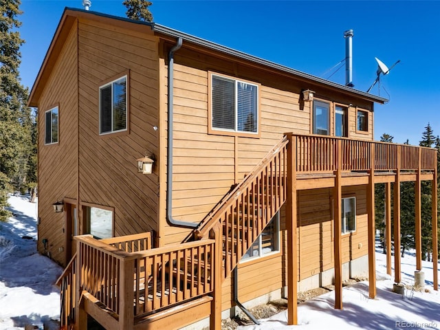 snow covered property featuring a wooden deck and stairs