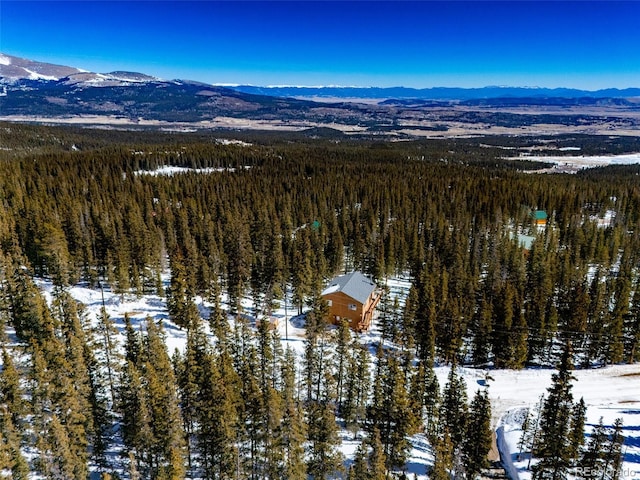 snowy aerial view with a mountain view and a forest view