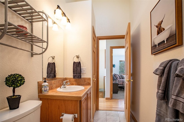 bathroom featuring a textured wall, vanity, and toilet