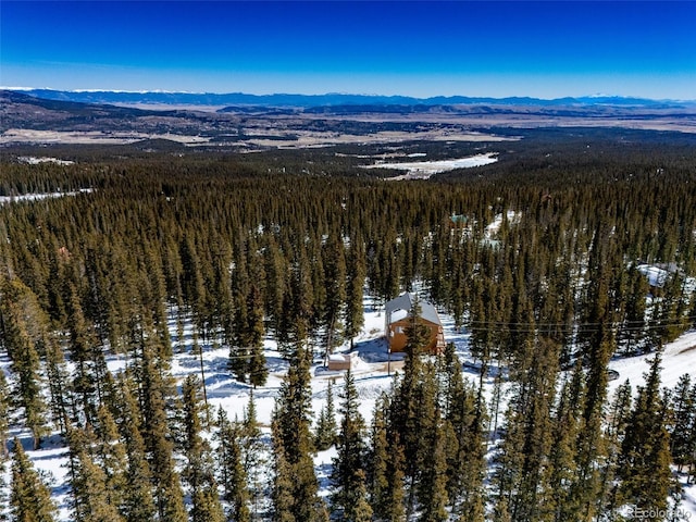 snowy aerial view featuring a mountain view and a forest view