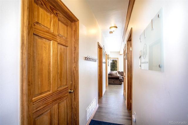 hall with visible vents, baseboards, and wood finished floors