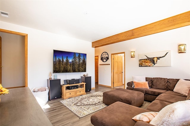 living area featuring baseboards, visible vents, beamed ceiling, and light wood finished floors