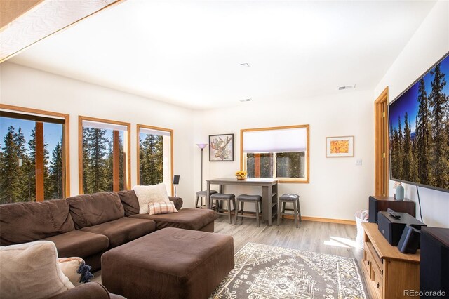 living area featuring visible vents, light wood-style flooring, and baseboards