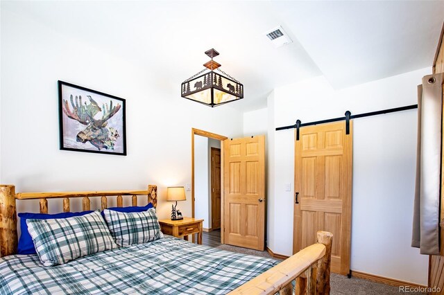 bedroom with carpet floors, visible vents, baseboards, and a barn door