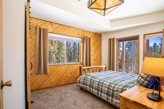 bedroom with carpet floors, multiple windows, and wooden walls