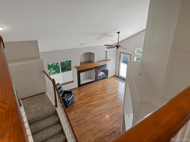 6900 W Grant Ranch Blvd Unit 49, Littleton, CO 80123 - stairway with wood finished floors, a ceiling fan, a lit fireplace, vaulted ceiling, and a textured ceiling