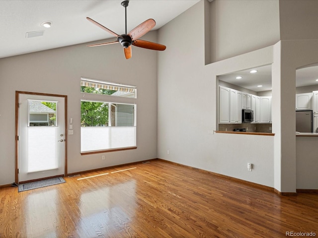 6900 W Grant Ranch Blvd Unit 49, Littleton, CO 80123 - unfurnished living room with ceiling fan, high vaulted ceiling, light wood-style flooring, arched walkways, and baseboards