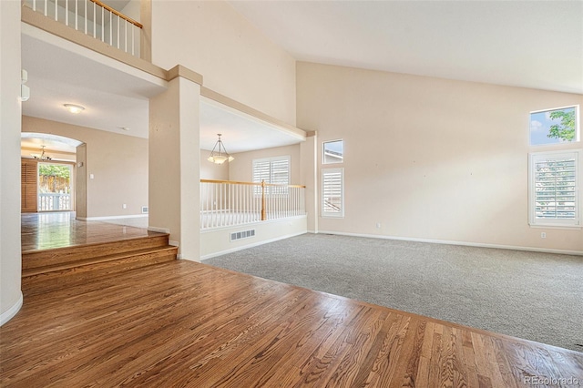 10155 Charissglen Ln, Littleton, CO 80126 - spare room featuring a high ceiling, baseboards, wood finished floors, arched walkways, and carpet