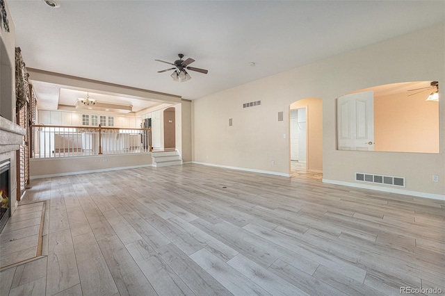 10155 Charissglen Ln, Littleton, CO 80126 - unfurnished living room with ceiling fan, arched walkways, a glass covered fireplace, and light wood-style flooring