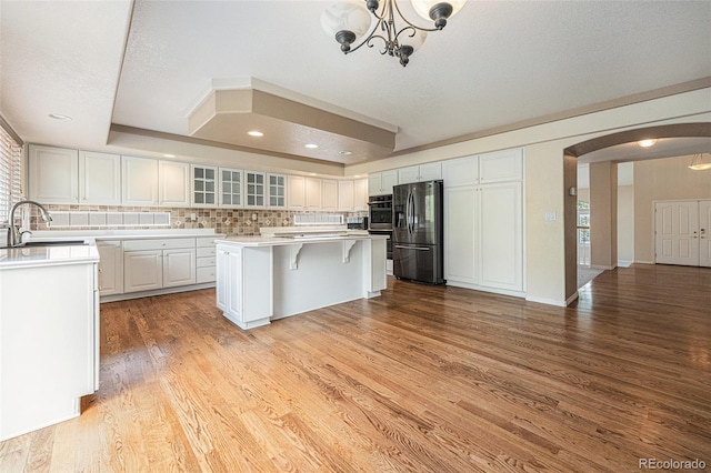 10155 Charissglen Ln, Littleton, CO 80126 - kitchen with stainless steel appliances, arched walkways, a sink, light wood-type flooring, and a chandelier