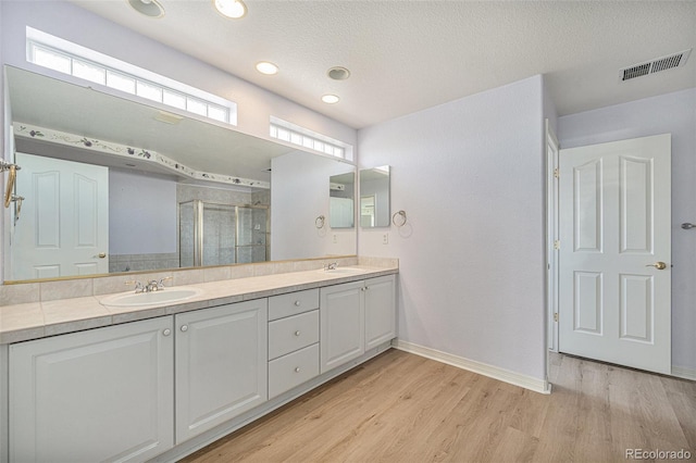 10155 Charissglen Ln, Littleton, CO 80126 - full bathroom with wood finished floors, a shower stall, double vanity, baseboards, and a textured ceiling