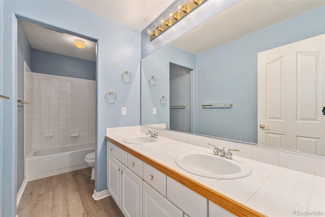10155 Charissglen Ln, Littleton, CO 80126 - full bathroom featuring toilet, wood finished floors, double vanity, baseboards, and a textured ceiling