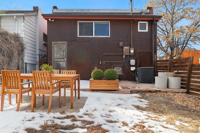 snow covered rear of property featuring central air condition unit