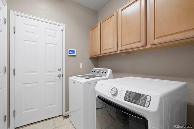 laundry room featuring separate washer and dryer, cabinet space, and light tile patterned flooring
