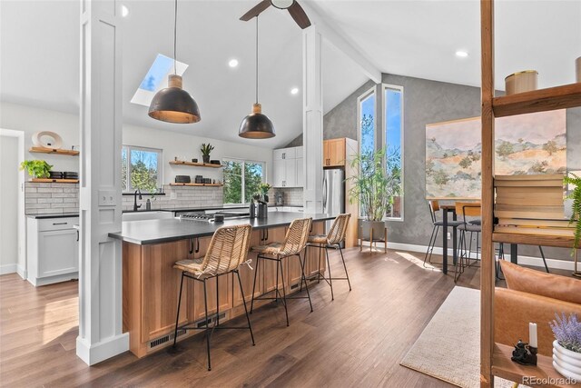kitchen featuring open shelves, lofted ceiling with beams, dark countertops, wood finished floors, and backsplash