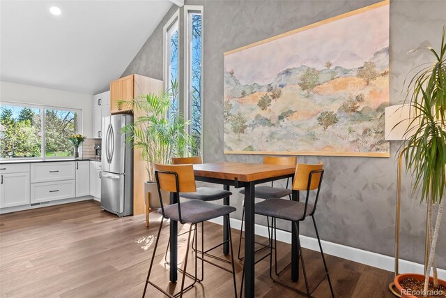 dining area with wallpapered walls and light wood finished floors