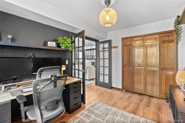 office featuring french doors, a textured ceiling, and light wood-style flooring