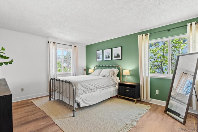 bedroom with a textured ceiling, baseboards, and wood finished floors