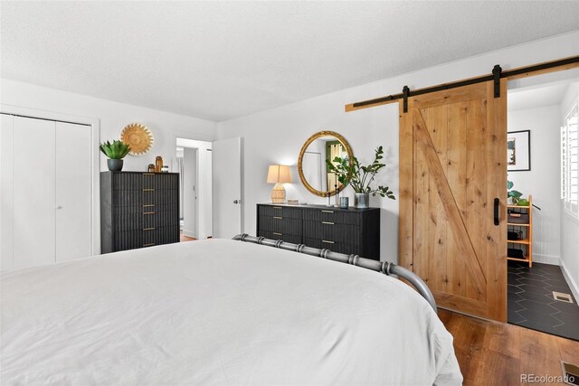 bedroom featuring baseboards, a closet, a barn door, and wood finished floors