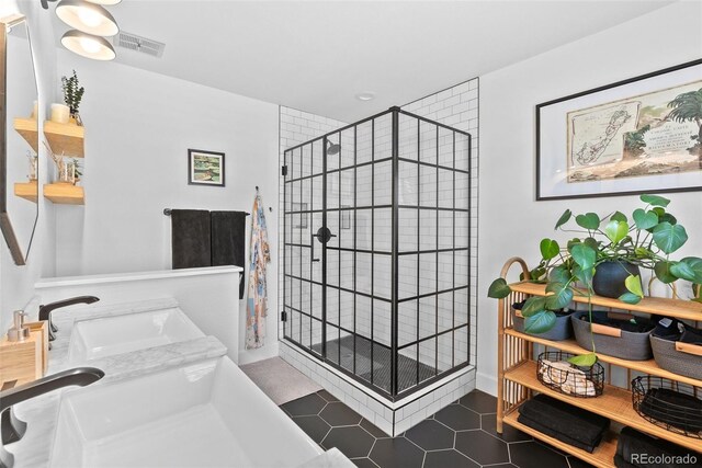 bathroom featuring a sink, tile patterned floors, a stall shower, and visible vents