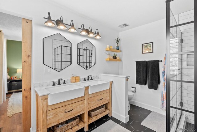 full bathroom featuring a sink, double vanity, toilet, baseboards, and visible vents