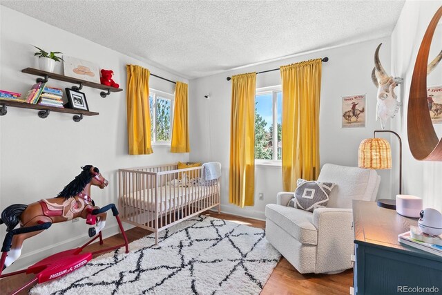 bedroom featuring a textured ceiling, wood finished floors, and a crib