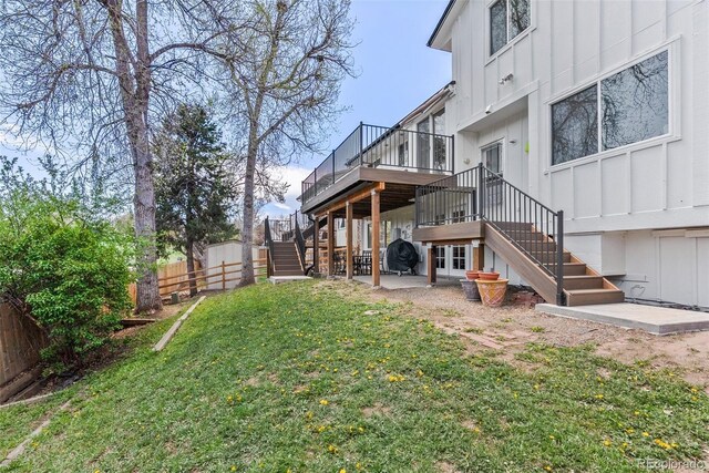 view of yard with stairway, a deck, fence, and a patio