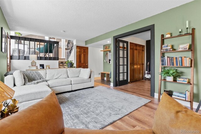 living room with a textured ceiling, baseboards, stairs, and wood finished floors