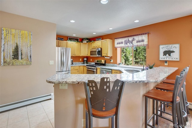 kitchen with a kitchen breakfast bar, light stone counters, appliances with stainless steel finishes, and a baseboard radiator