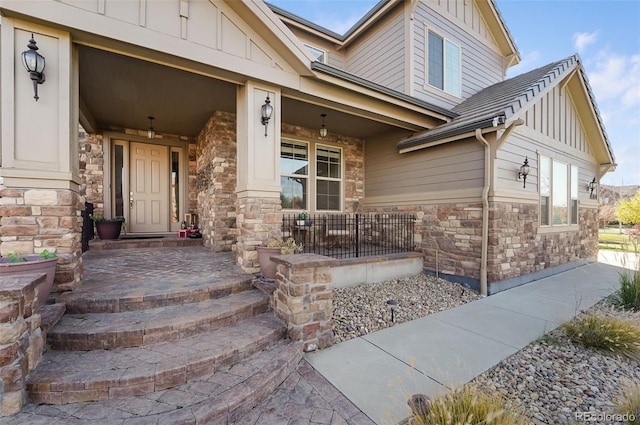 doorway to property featuring board and batten siding, stone siding, and a porch