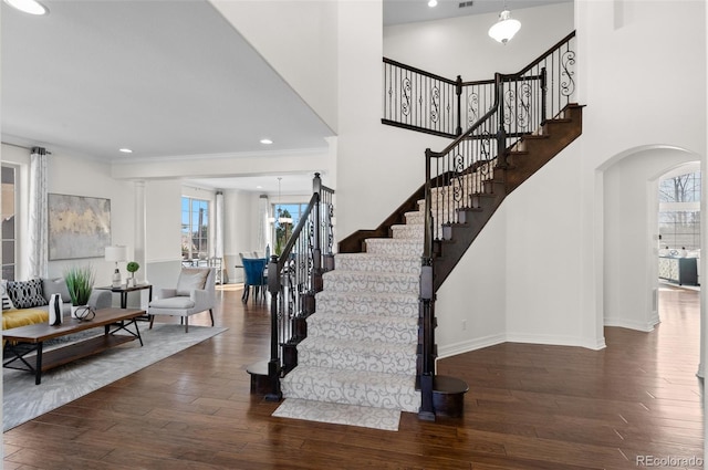 foyer with arched walkways, recessed lighting, baseboards, stairway, and wood-type flooring