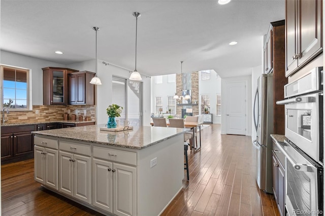 kitchen with a center island, tasteful backsplash, glass insert cabinets, freestanding refrigerator, and a sink