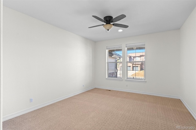 spare room with light carpet, ceiling fan, and baseboards