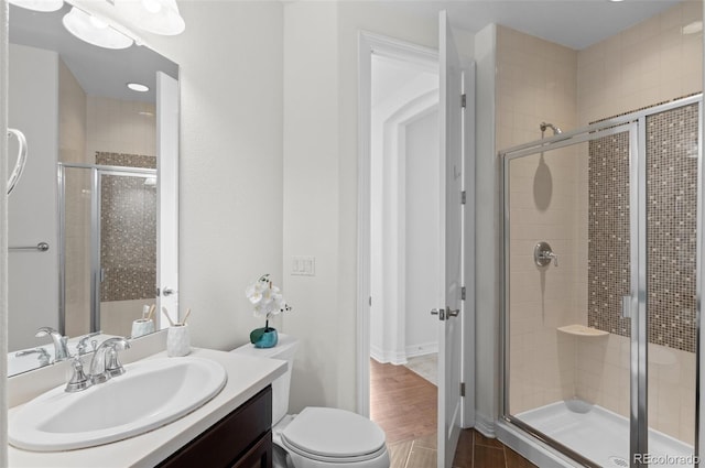 bathroom featuring toilet, a shower stall, and vanity