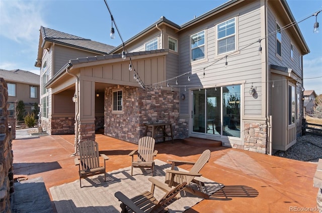 rear view of property featuring stone siding and a patio