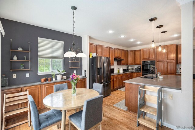 kitchen featuring stainless steel fridge, brown cabinets, a sink, under cabinet range hood, and recessed lighting
