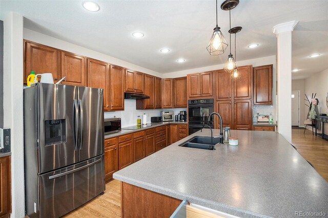 kitchen with black appliances, a sink, under cabinet range hood, brown cabinets, and recessed lighting