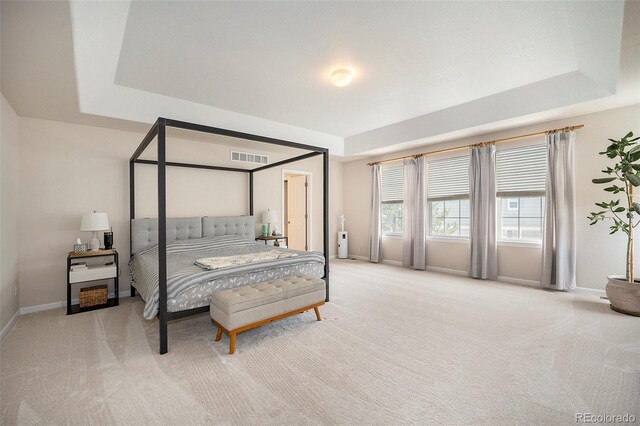 bedroom with carpet, a tray ceiling, and baseboards