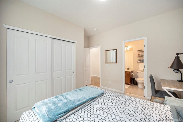 bedroom featuring a closet, baseboards, light colored carpet, and connected bathroom