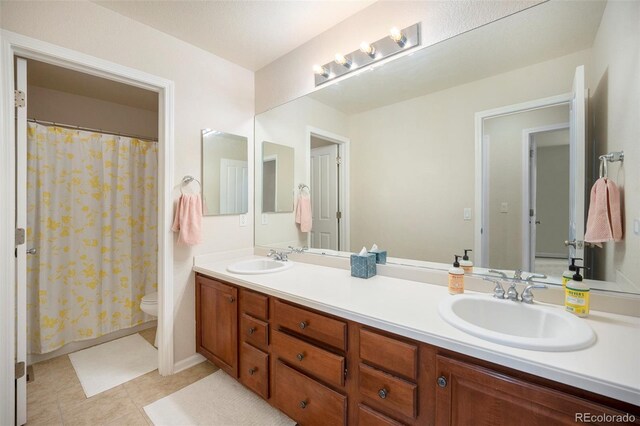 bathroom with toilet, double vanity, a shower with curtain, and baseboards