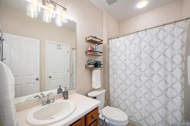 bathroom featuring vanity, toilet, a shower with curtain, and a textured wall