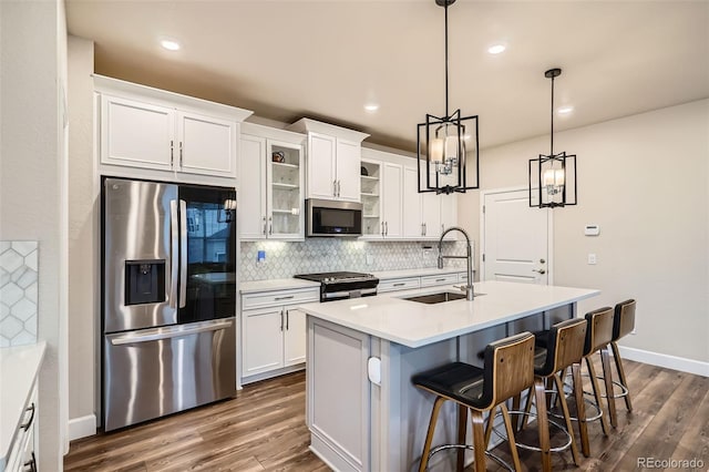 kitchen with appliances with stainless steel finishes, a sink, backsplash, white cabinets, and dark wood-style flooring